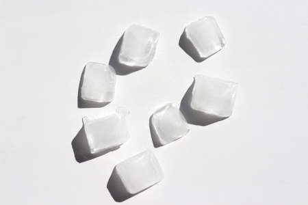 Ice cubes on white background. Top view, copy space. Hard light, shadowの写真素材