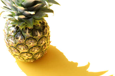 Pineapple on yellow background. Summer background with tropical exotic fruit. Top view, copy space. Hard light, shadow.の写真素材
