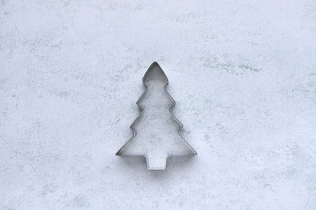 Cookie cutter in christmas tree shape on gray concrete background with copy space. Christmas...