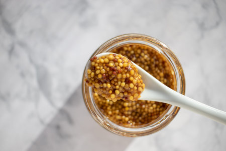 Mustard in a glass jar with a spoon on a marble backgroundの写真素材