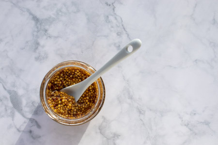 Mustard in a glass jar with a spoonの写真素材