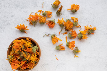 Dried calendula flowers in a wooden bowl on white background.の写真素材