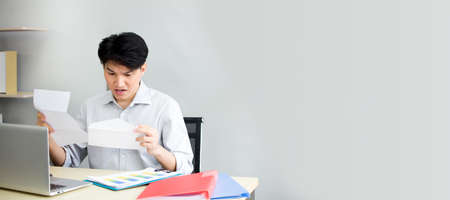 The male employee was confused and shocked when he received a letter fired from work. The frustrated young man is worried about the high bill tax invoice, overdue debt notification money problem.の写真素材
