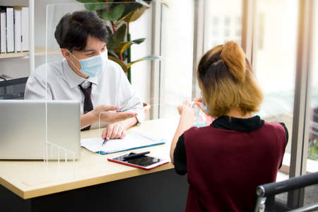 Asian male employees worked in offices during the outbreak of the coronavirus (COVID-19), He wears a face mask regularly to protect himself.の写真素材