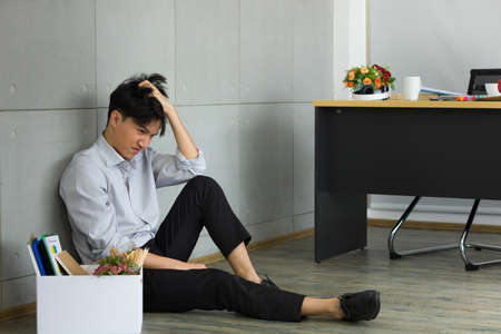 Asian man is stressed because he has been fired from work. Dismissed employees Due to the economic downturn and to the epidemic COVID-19.の写真素材