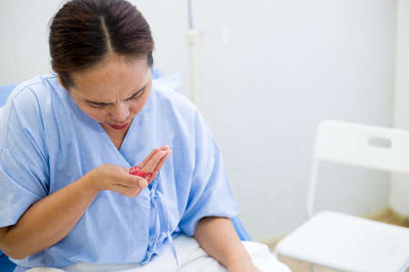 Asian female patient with hemoptysis symptoms while sitting on the hospital bed.の写真素材