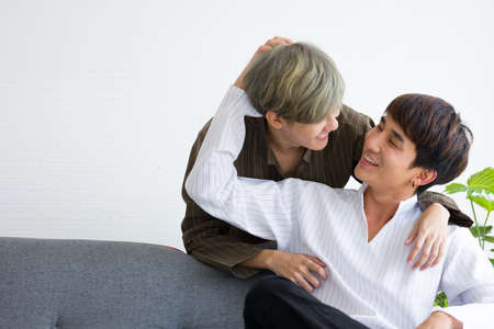 Happy Asian male homosexual or gay couples are sitting on the sofa bed, Both of them are making eye contact together in the mood of love and good relationship. Concept of LGBTQ pride.の写真素材
