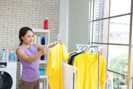 Housewife is drying clothes on the clothesline after washing. Asian young woman is happily doing housework.の写真素材