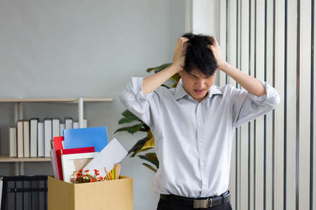Asian man is stressed because he has been fired from work. Dismissed employees Due to the economic downturn and to the epidemic COVID-19.の写真素材