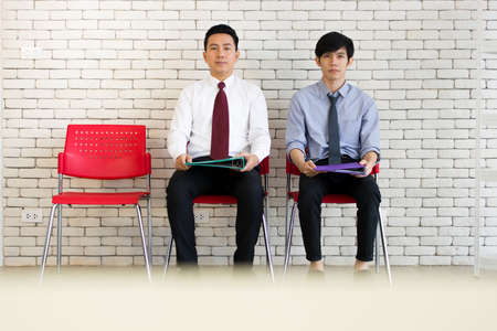 People waiting for a new job interview. Recruiting people to work. Two men sitting and waiting at the chair.の写真素材