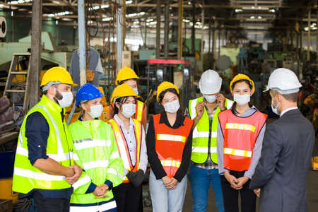 Group of Factory workers are meeting in the morning to plan the work each day at the warehouse with each person wearing a mask.の写真素材