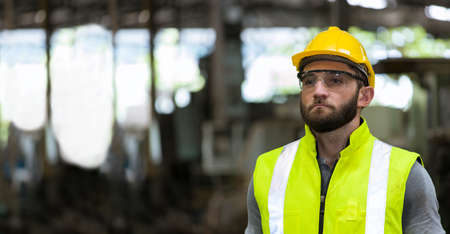 Portrait of the caucasian handsome bearded engineer, He was wearing safety gear and standing in the factory.の写真素材
