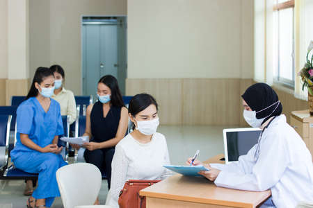 Many people wearing a surgical mask comes to the hospital for examination.の写真素材