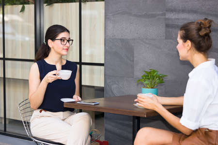 Caucasian woman sat sipping tea and chatting along the aisle.の写真素材