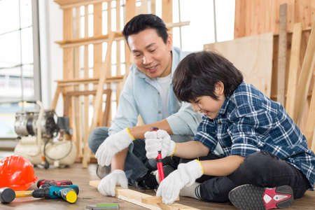 Asian father is teaching his son woodworking.の写真素材