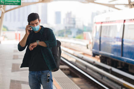 Caucasian man wearing surgical masks waiting to board the public train at rush hour.の写真素材