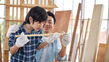 Asian father teaches his son to do carpentry at home.の写真素材
