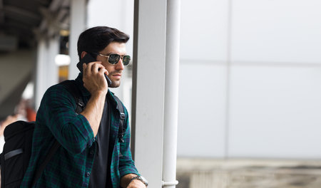 European male tourist stands on a bridge while  using the phone to call for directions.の写真素材