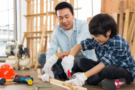 Asian father is teaching his son woodworking.の写真素材