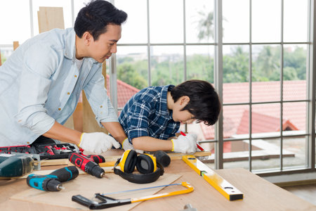A lovely son helps his father do carpentry at home.の写真素材
