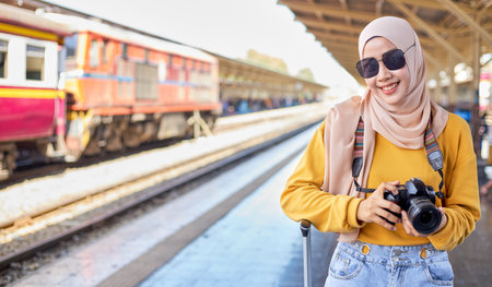 Female Islamic tourists hold cameras while waiting to travel.の写真素材