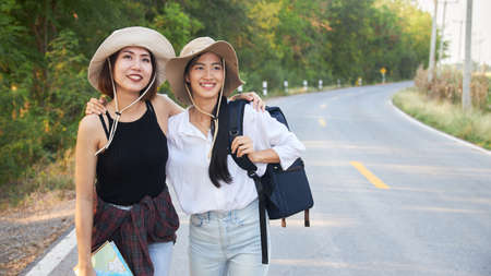 Two Asian female travelers walking on a country road.の写真素材