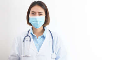 Portrait of a female doctor wearing a mask and uniform with a stethoscope on white background.の写真素材