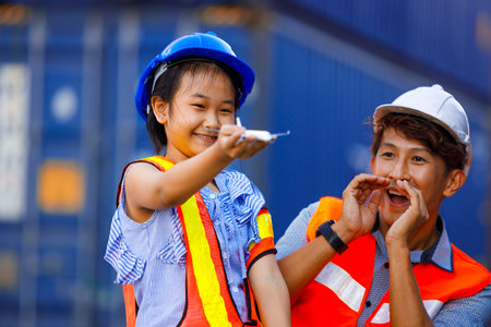 Cute girl dreams of becoming an engineer. Asian father wearing safety clothes is happily playing toy plane with daughter. Promoting children's learning, imagination and cognitive development.の写真素材