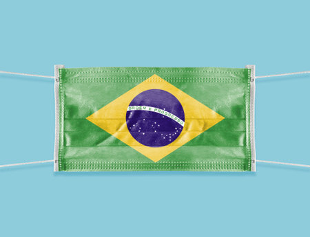 National flag of Brazil on a disposable surgical mask. Blue background.の写真素材