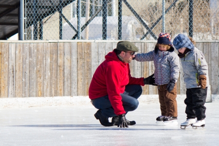 Family having fun at the outdoor skating rink in winter.の写真素材