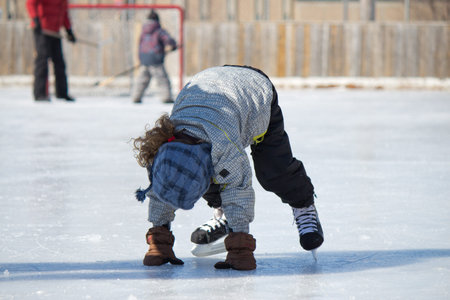 Child playing and skating at the outdoor skating rink in winter.の写真素材