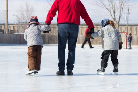 Family having fun at the outdoor skating rink in winter.の写真素材