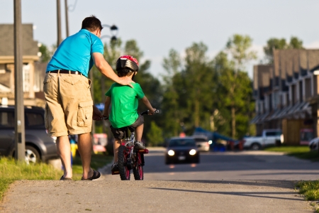 Child learning to ride a bicycle with fatherの写真素材
