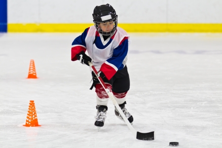 Child skating with a puck at ice hockey practiceの写真素材