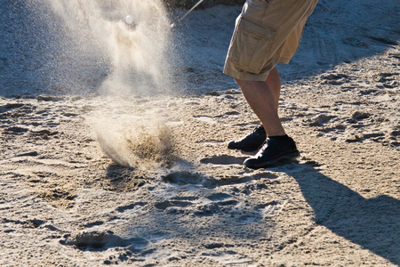 Golf player hitting the ball from the sand bunkerの写真素材