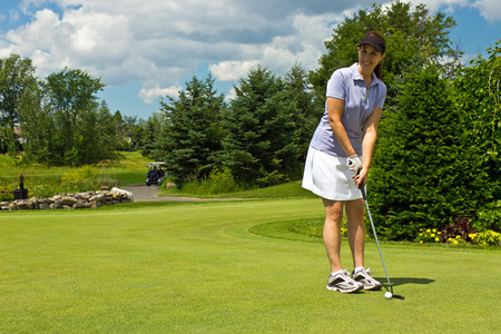 Woman golfer putting the golf ball on the greenの写真素材
