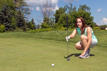 Woman takes aim for her putt on the golf greenの写真素材