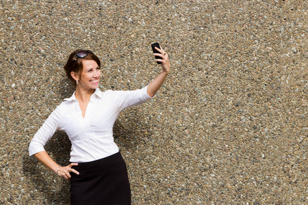 Young attractive business woman executive using her smart phone to take a selfieの写真素材