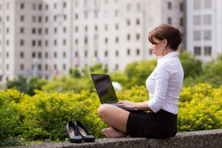 Young business woman kicks off her shoes and casualy works in the cityの写真素材