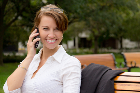 Attractive woman talks on mobile phone in the parkの写真素材