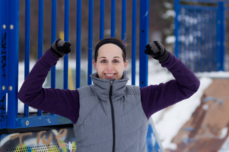 Fit attractive sporty woman outdoors on cold winter day flexing biceps. Fit healthy lifestyle...
