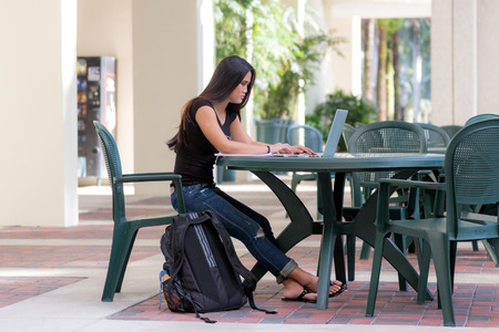 Attractive young woman student working on laptop computer doing homework assignmentの写真素材