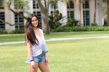 Portrait of a casual smiling young pretty Asian girl outdoorsの写真素材