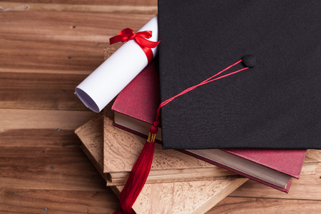 Black graduation cap and diploma on a stack of booksの写真素材