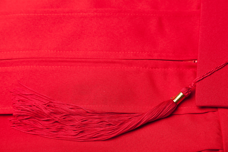 Red graduation gown and mortarboard on a flat surfaceの写真素材