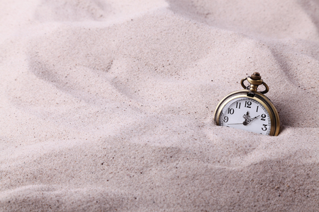 Vintage pocket watch partially buried in the sandの写真素材