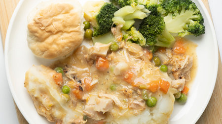 chicken stew with mashed potatoes and vegetables on a white plate.の写真素材