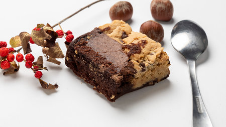 Chocolate cake with hazelnuts and a spoon on a white backgroundの写真素材