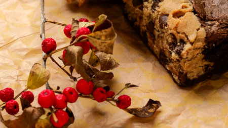 Chocolate cake with berries and dry leaves on a brown paper backgroundの写真素材