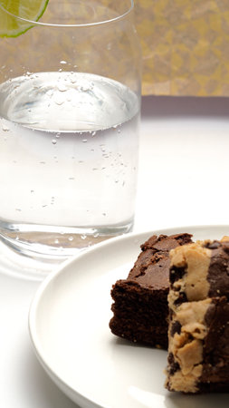 Chocolate brownies and a glass of water on a white backgroundの写真素材